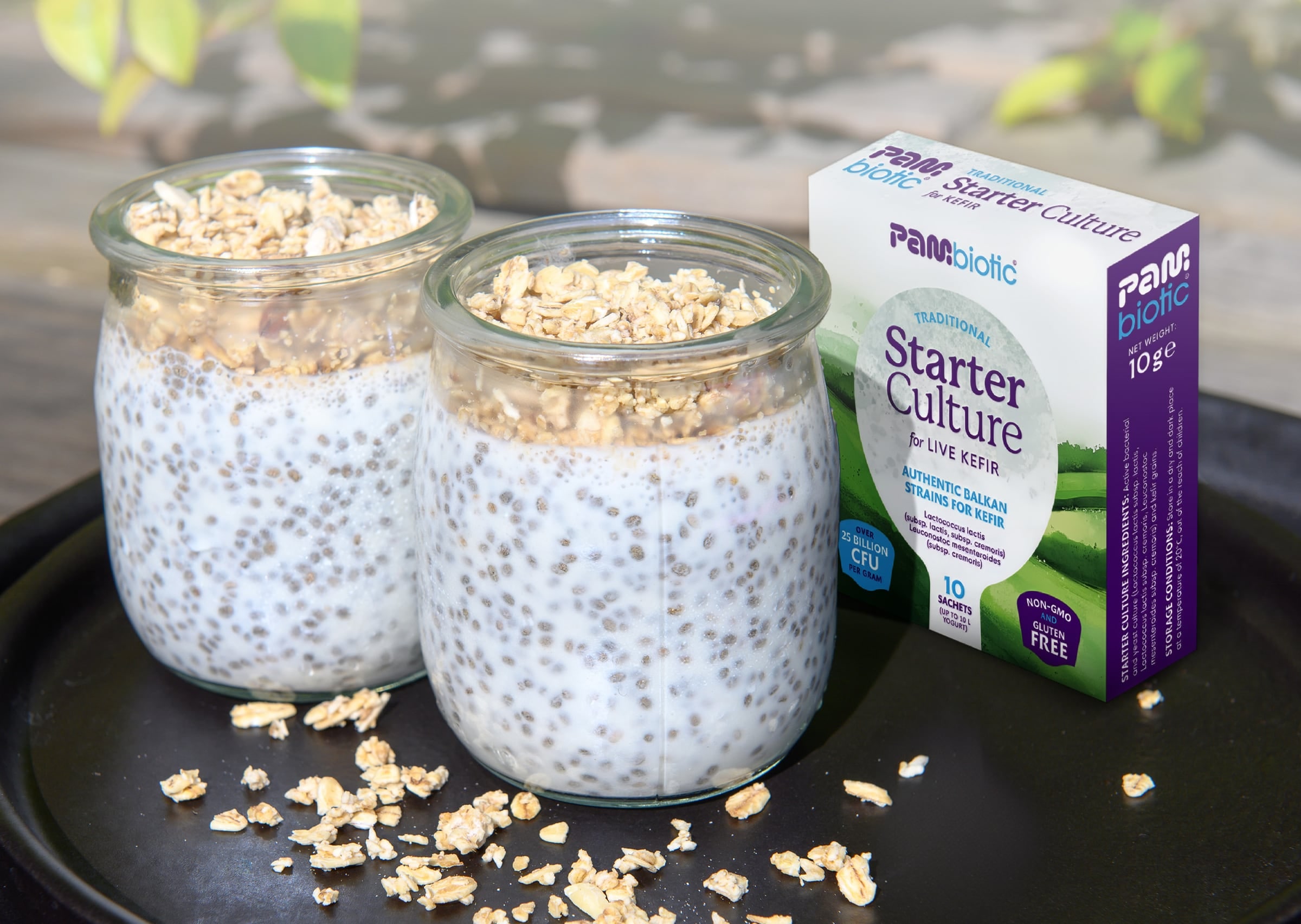Two jars of homemade kefir with oats next to the Pambiotic kefir starter box